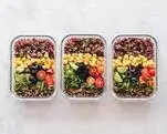 Photo of three containers with prepared meals filled with colorful vegetables inside them.
