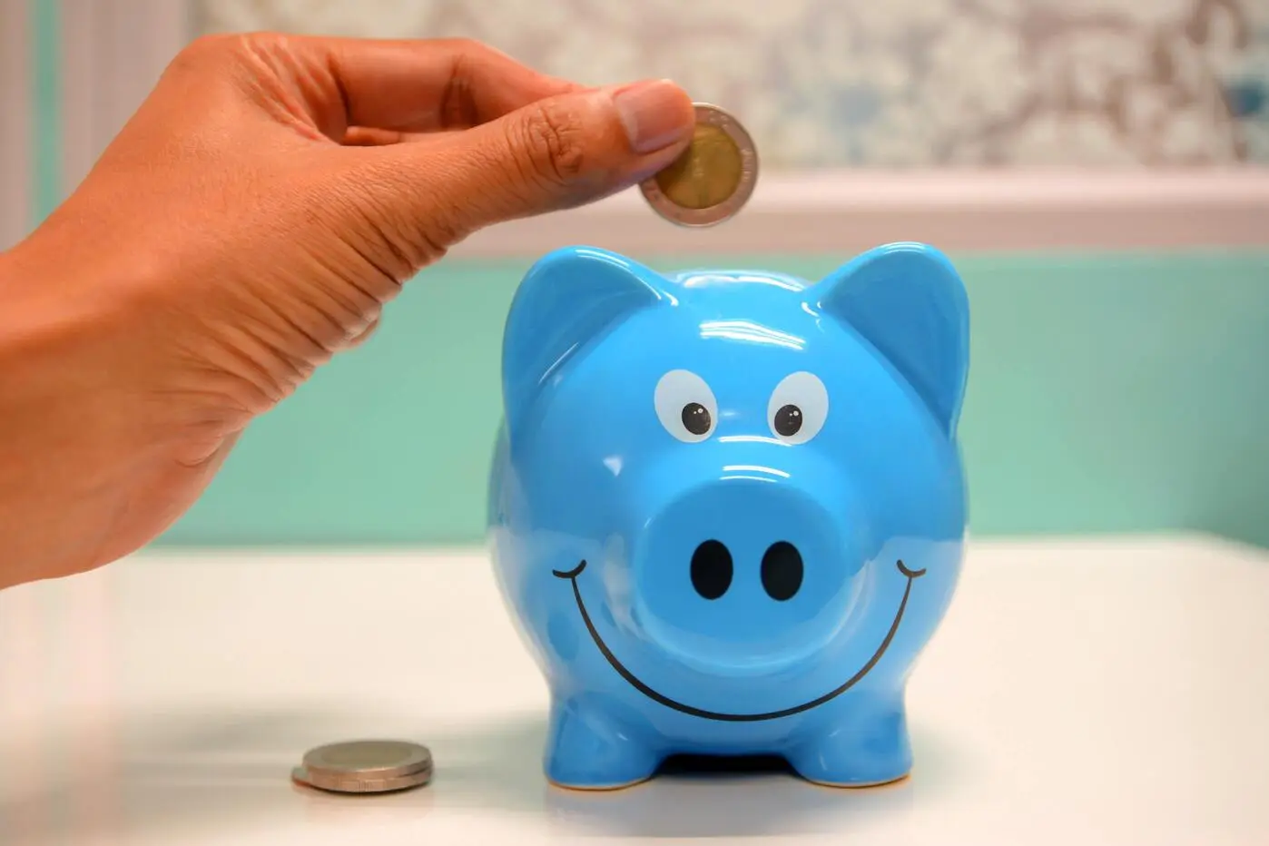 Hand inserting coin into piggy bank.